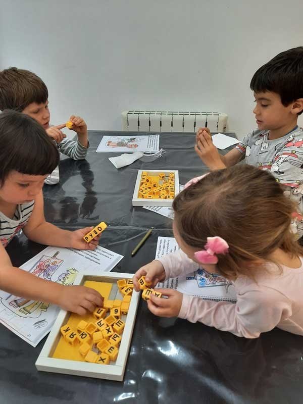 Niños jugando con juegos de letras en una mesa en el centro cultural.