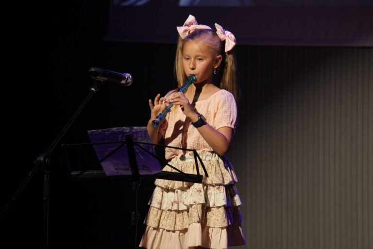 Noia interpretant el clarinet a l'escenari amb micròfon i partitura.