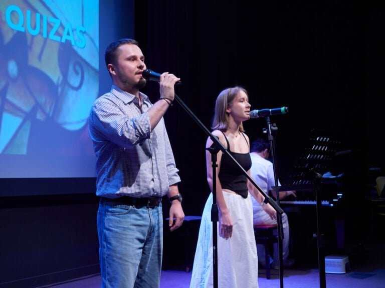 Jove i adult cantant en un concurs al centre cultural.