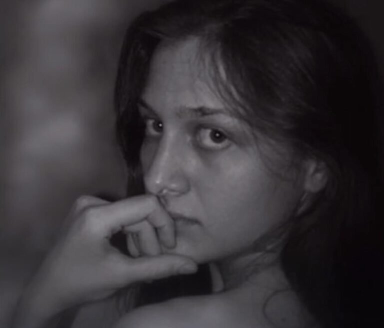 Woman with a pensive expression, touching her face with her hand.