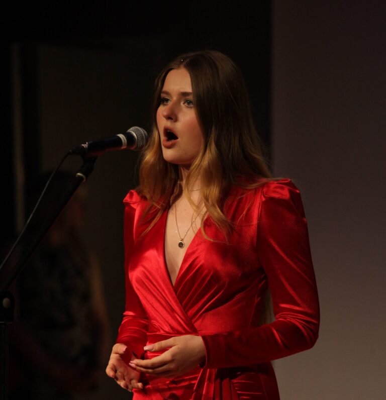 Jove dona cantant a l'escenari amb un micròfon a la mà.