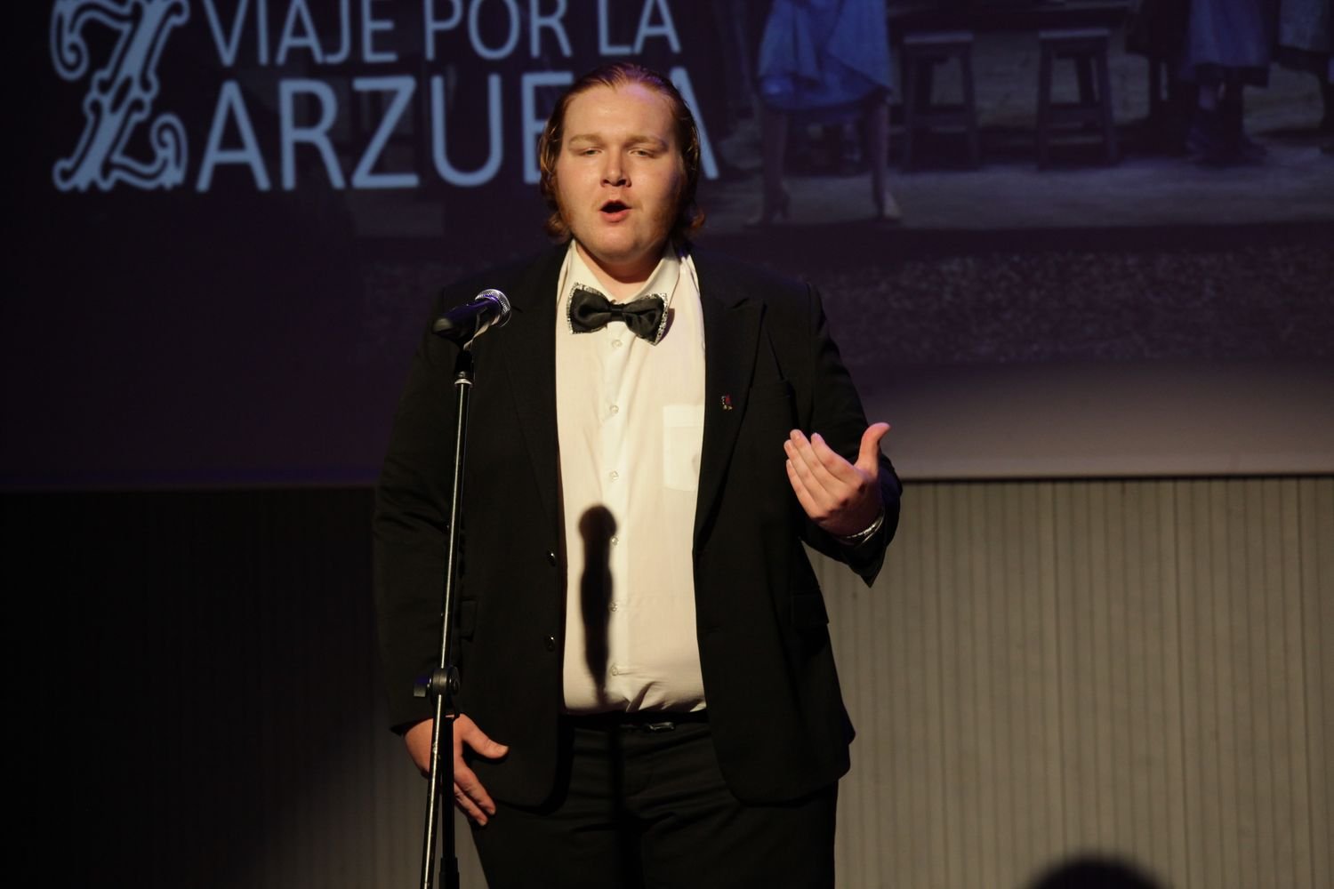 Hombre cantando en un concierto de canto clásico en un escenario.