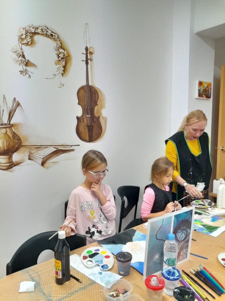 Niñas y profesora en taller de pintura en centro cultural.