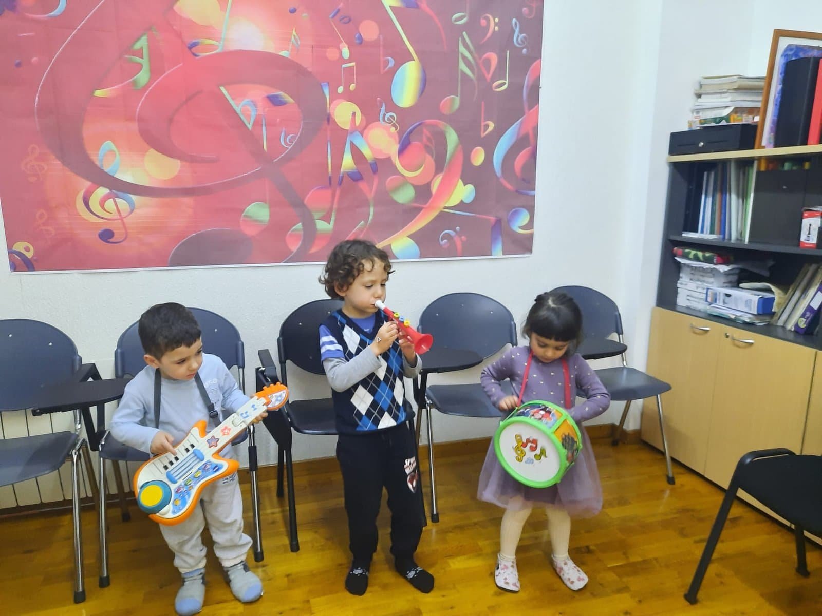 Tres nens tocant instruments en una classe de música.