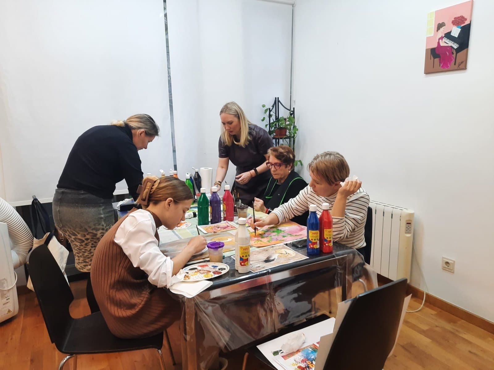 Personas participando en taller de pintura en interior.