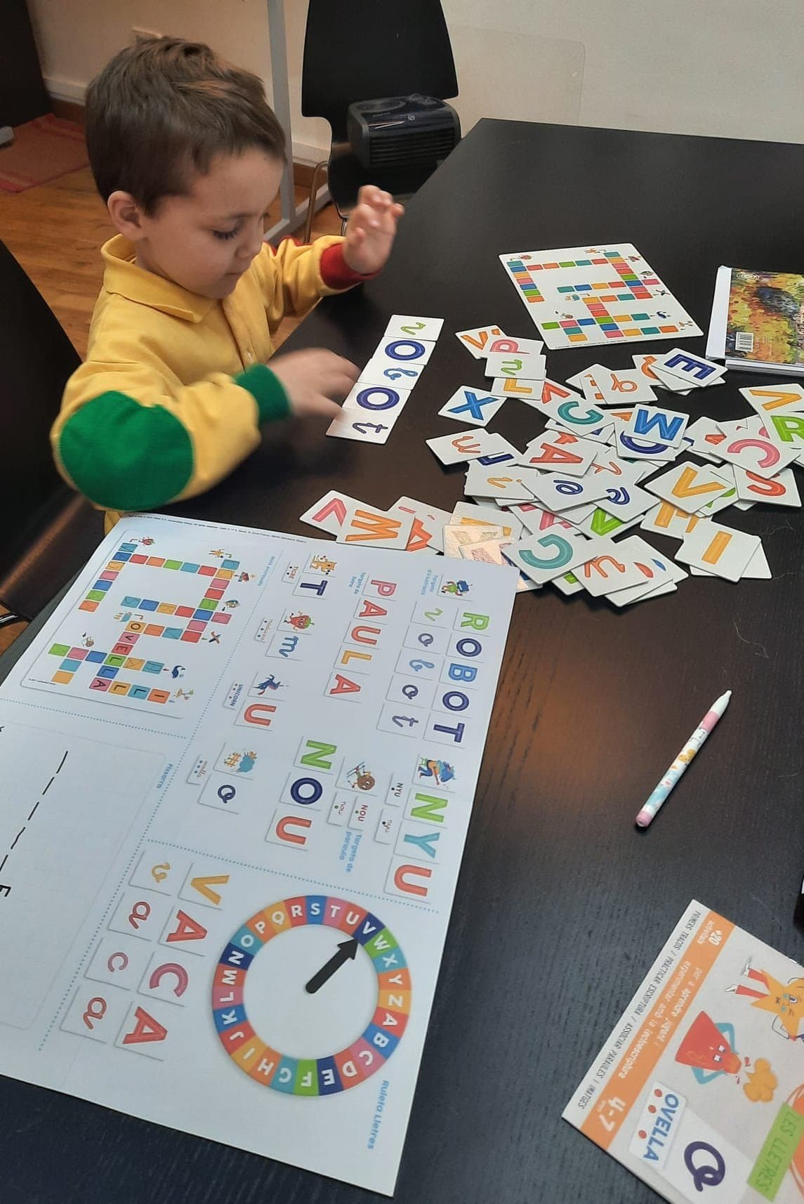 Niño jugando con juegos de letras y números en una mesa.