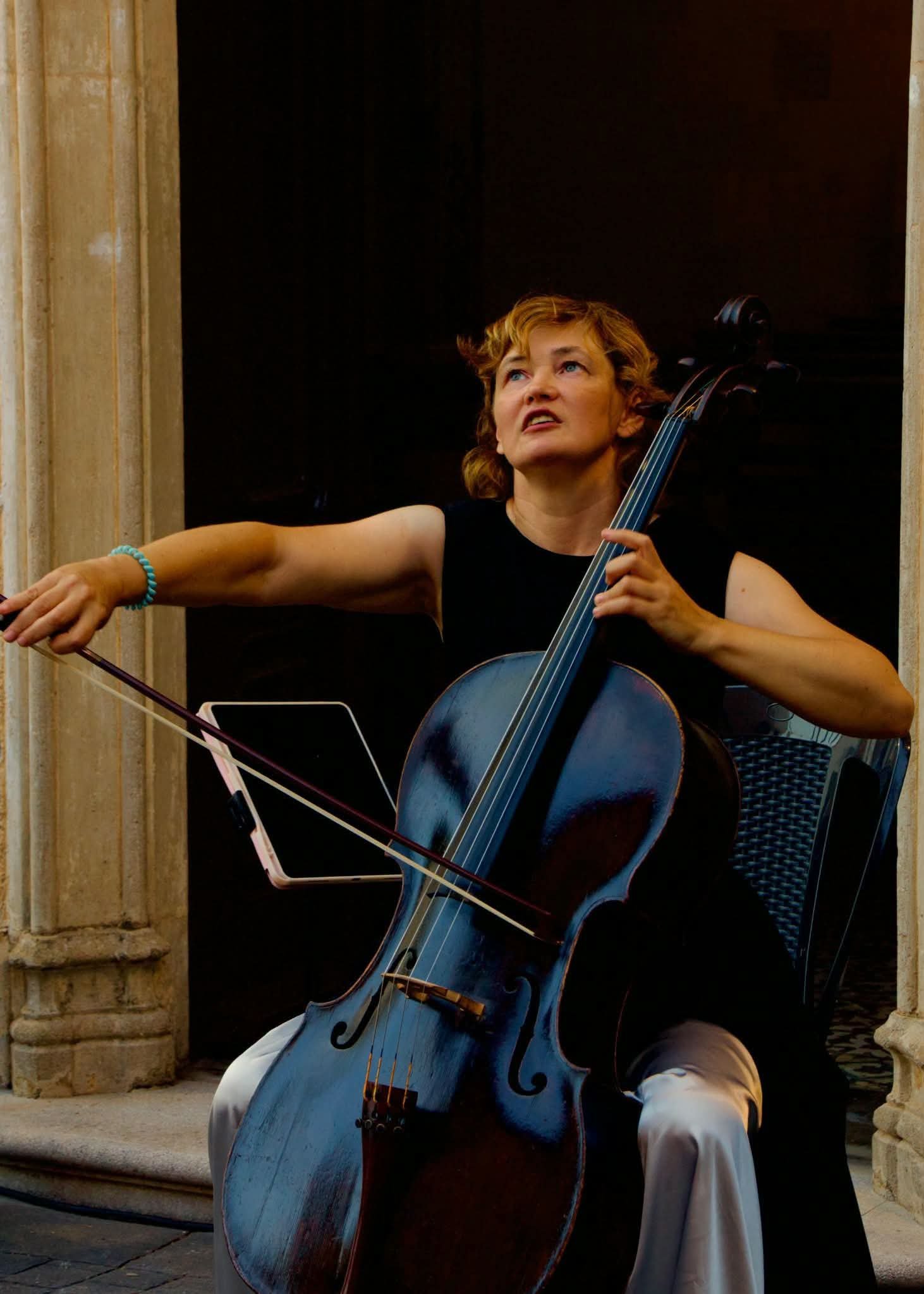 Mujer tocando violonchelo en escenario con expresión emotiva.