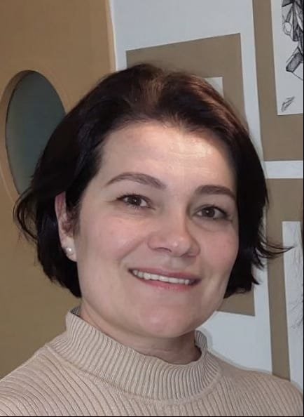 Mujer con cabello castaño oscuro y sonrisa en centro cultural.