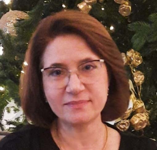 Portrait of Marina Sipchenko in front of a decorated Christmas tree.