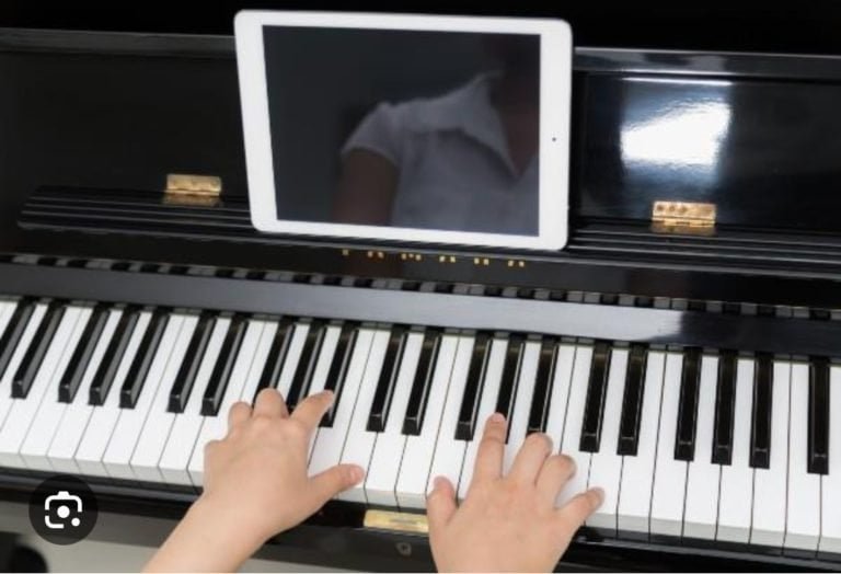 Niños tocando piano con tablet en centro cultural.